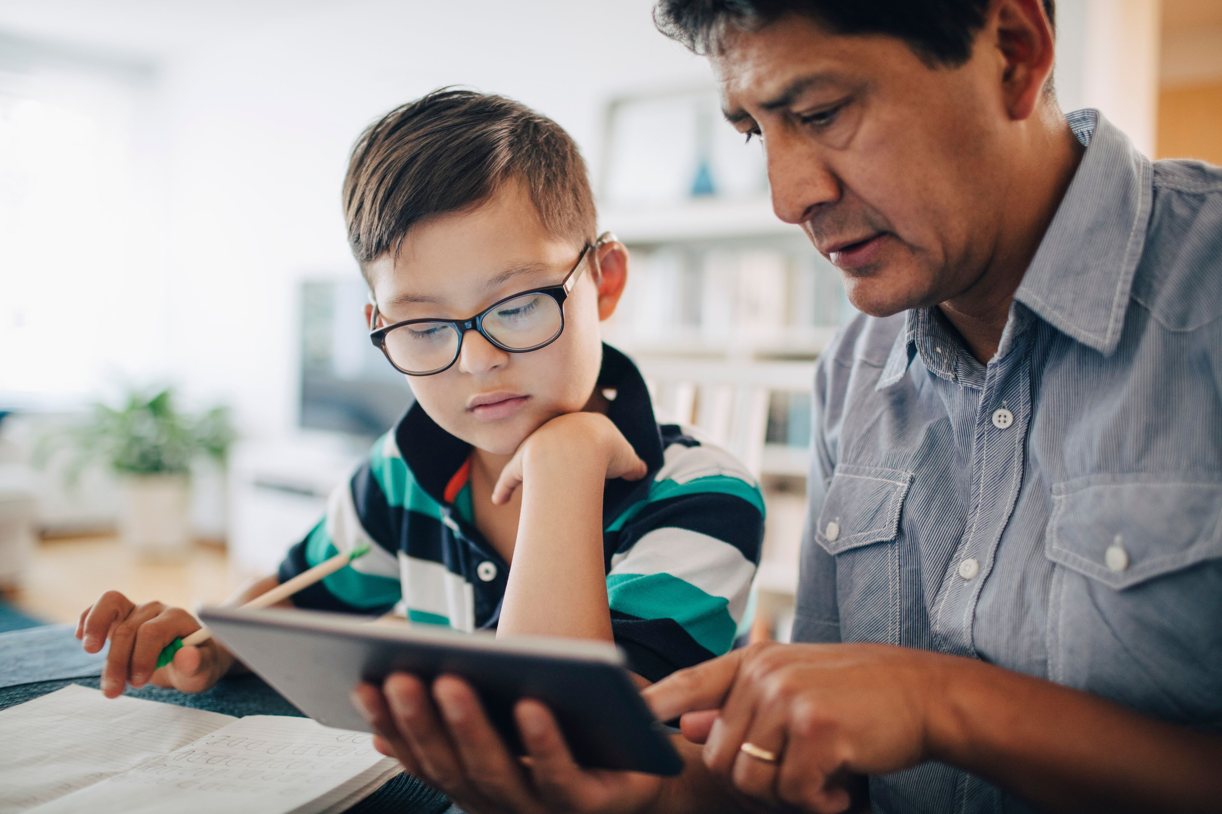 Father and son doing school work together using a smartphone